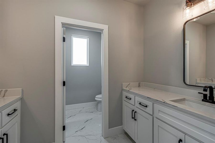 Bathroom with baseboards, toilet, marble finish floor, and vanity