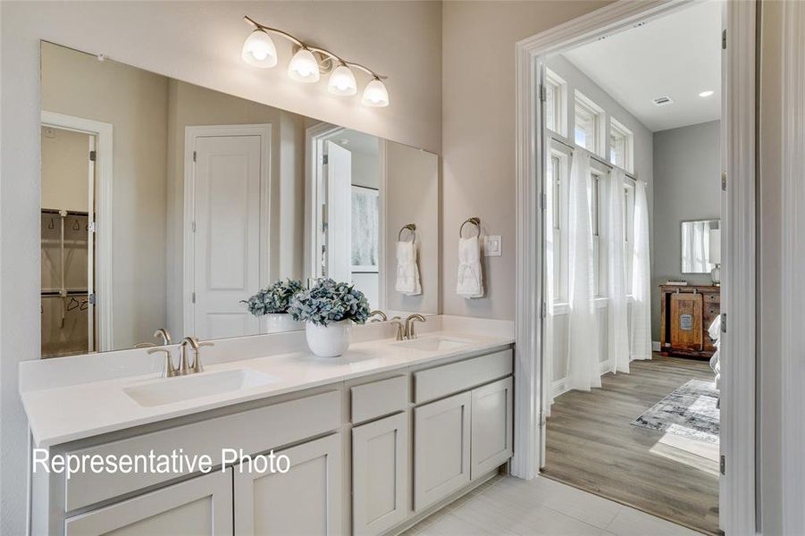 Bathroom featuring a dual sink vanity with light-colored cabinetry and a large mirror