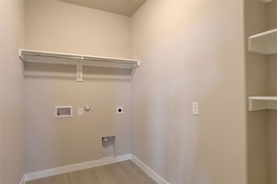 Washroom with electric dryer hookup, hookup for a gas dryer, hookup for a washing machine, and light hardwood / wood-style flooring