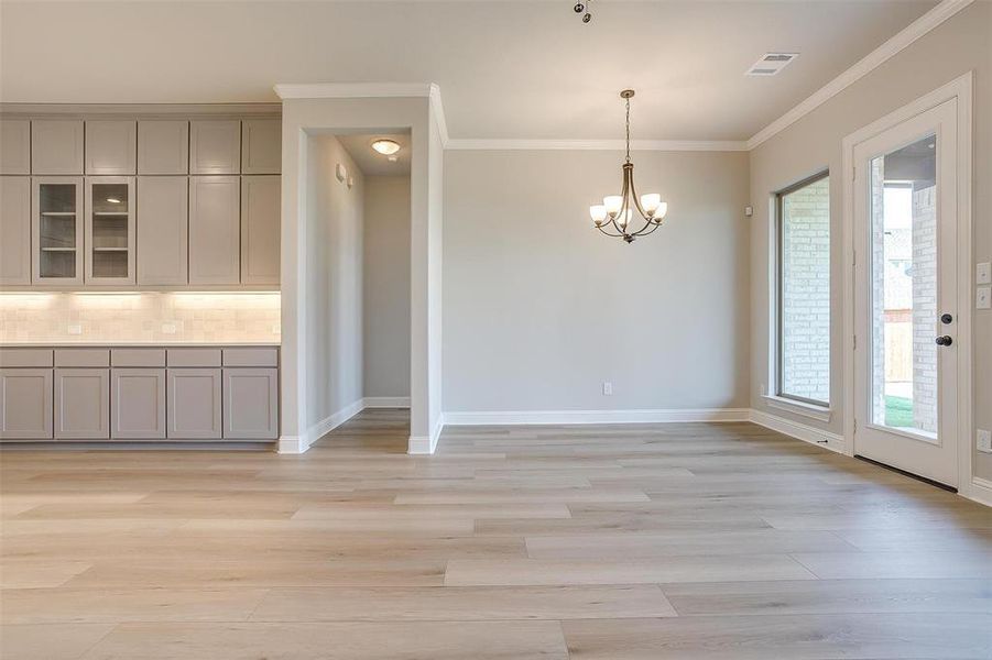 Unfurnished dining area with crown molding, light hardwood / wood-style floors, and a chandelier