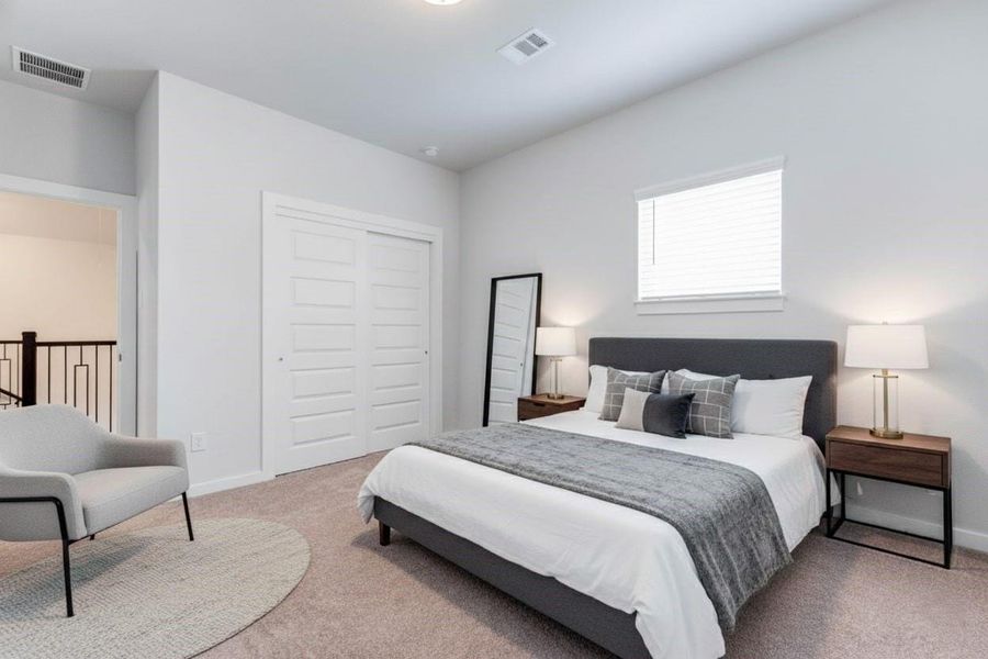A cozy secondary bedroom upstairs features soft carpeting, a large window, and a double-door closet for added storage. Its location just off the game room makes it ideal for a flexible guest room, study, or creative space. This photo has been virtually staged for visual reference.