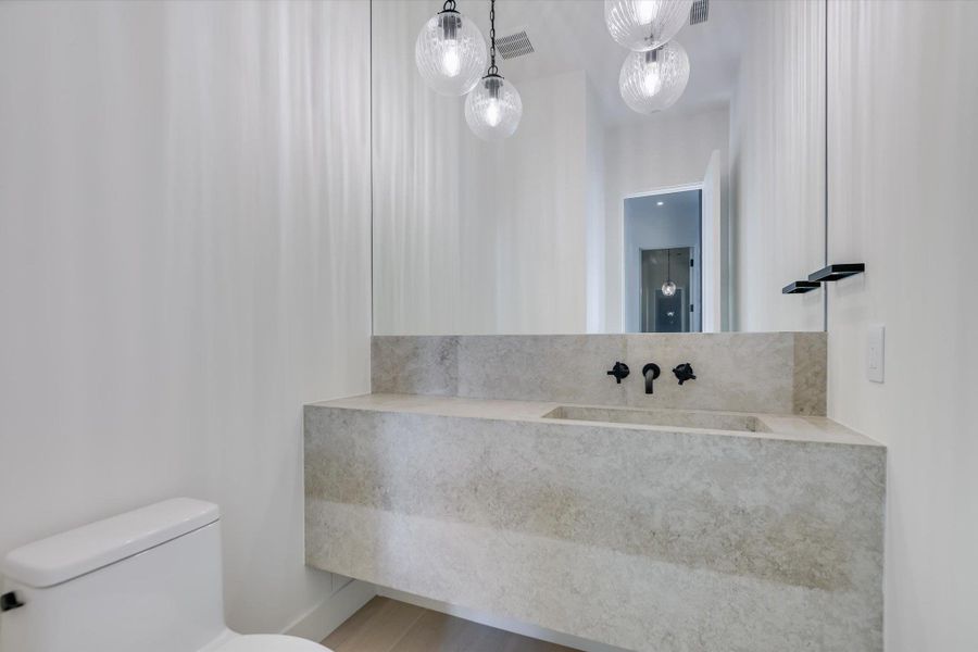 A chic bathroom presents a floating stone vanity, integrated sink, and modern pendant lighting.