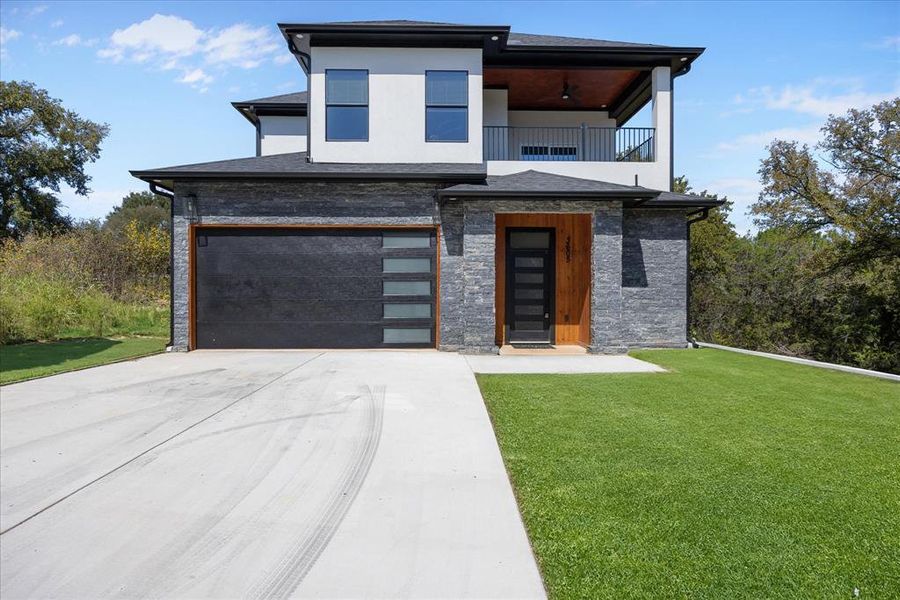 View of front of home featuring a garage, a balcony, and a front yard