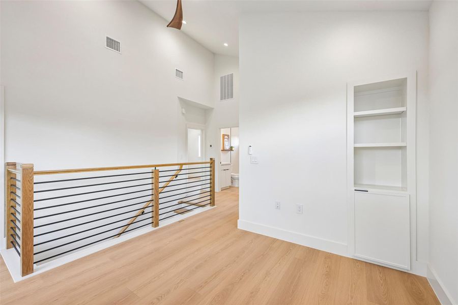 A well-lit loft area with a modern railing design and built-in shelving.