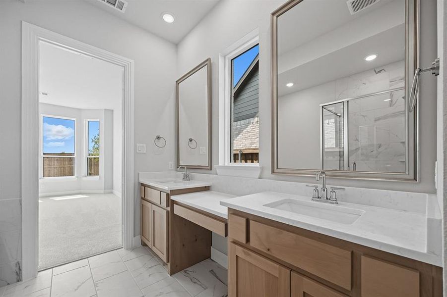 Full bathroom featuring a marble finish shower, light marble finish flooring, two vanities, and recessed lighting