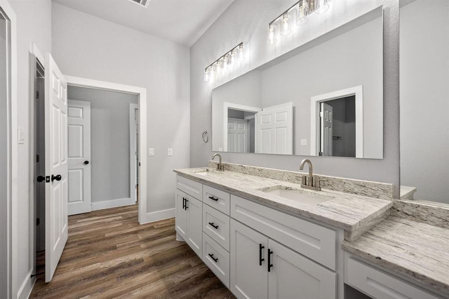 Full bathroom featuring double vanity and dark wood-type flooring