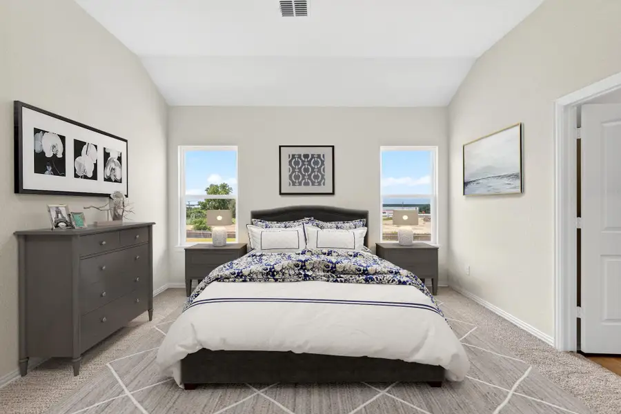 High vaulted ceilings and twin windows frame this comfortable bedroom retreat.