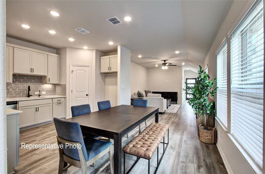 Dining space with ceiling fan, light hardwood / wood-style flooring, vaulted ceiling, and sink