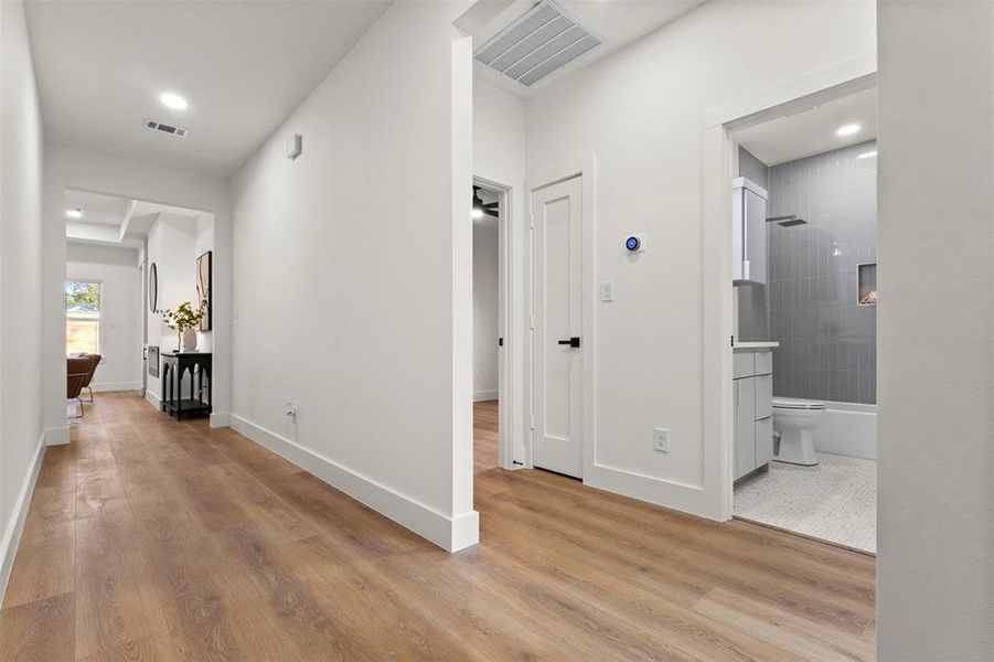 Hall with light wood finished floors and recessed lighting