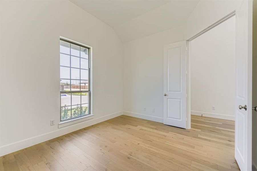 Unfurnished room with light wood-type flooring and vaulted ceiling Unfurnished room with light wood-type flooring and vaulted ceiling