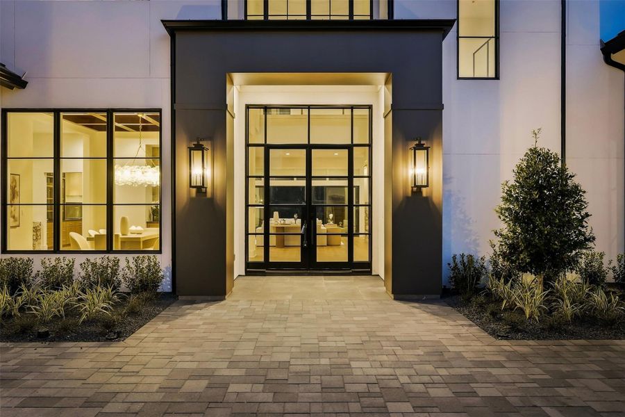 A breathtaking, modern entrance welcomes your guests with large steel glass doors and windows, flanked by ambient outdoor lighting. A breathtaking, modern entrance welcomes your guests with large steel glass doors and windows, flanked by ambient outdoor lighting.