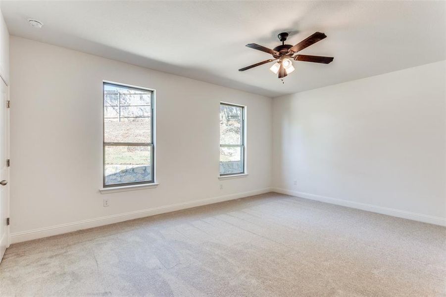 Carpeted empty room featuring a healthy amount of sunlight and ceiling fan