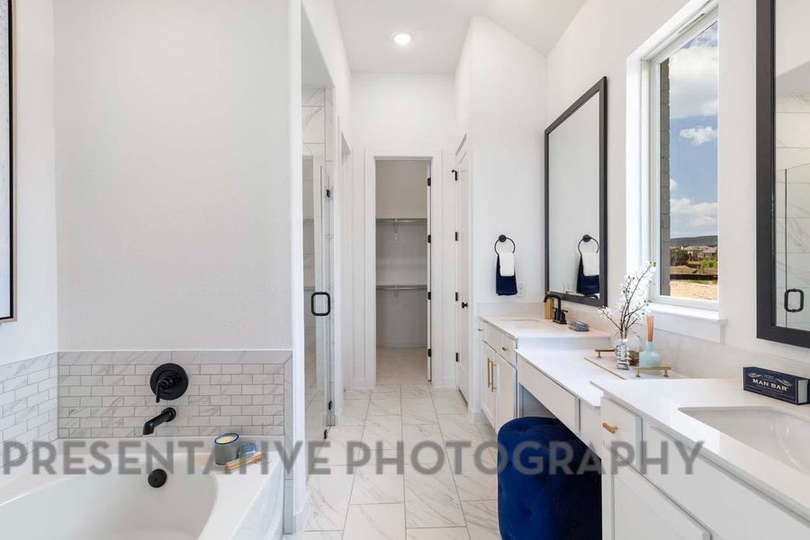 Bathroom featuring a sink, marble finish floor, a bath, double vanity, and a stall shower