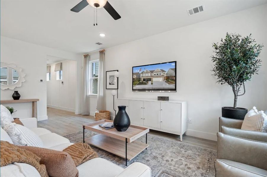 Living area featuring light wood-style floors, ceiling fan, and baseboards