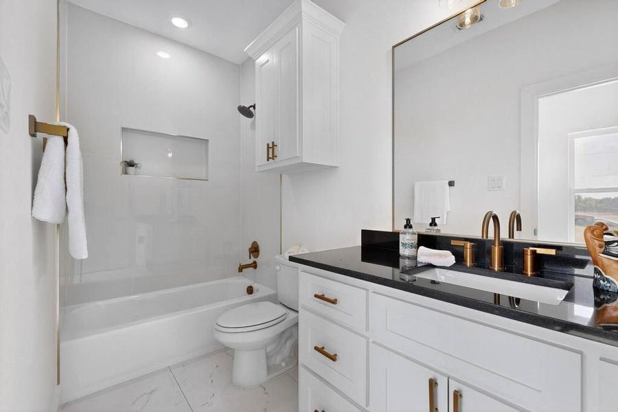 Bathroom featuring shower / bathtub combination, vanity, and light marble finish floors