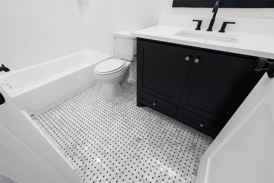 This secondary bath features a tub/shower combo with marble floor details.