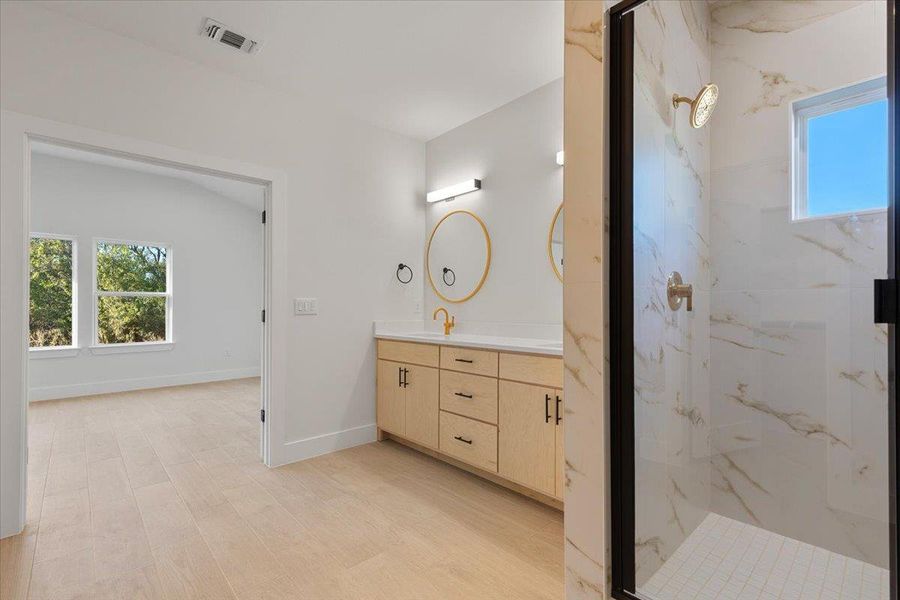 Full bathroom with a marble finish shower, vanity, and light wood-type flooring Full bathroom with a marble finish shower, vanity, and light wood-type flooring