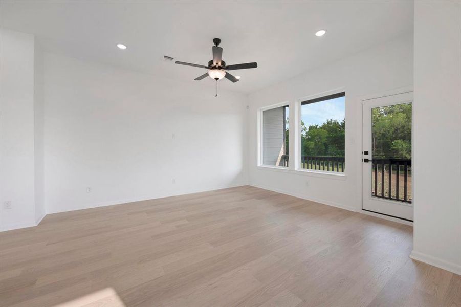 Spacious room featuring light wood-finish flooring, recessed lighting, and a contemporary ceiling fan