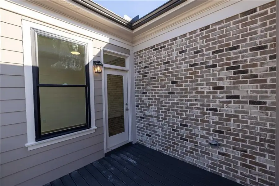 View of exterior entry with brick siding and a wooden deck