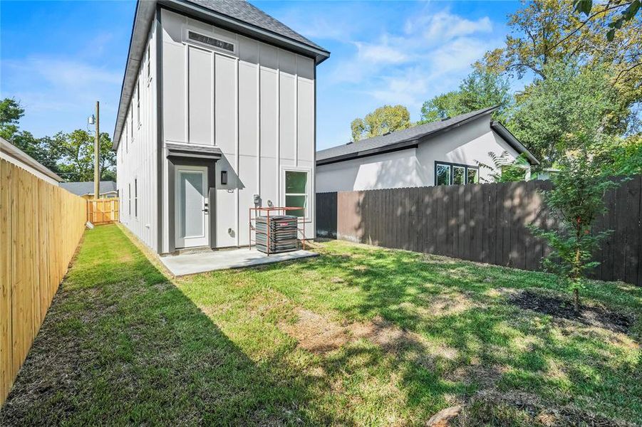Rear view of property with board and batten siding, a fenced backyard, roof with shingles, and a patio