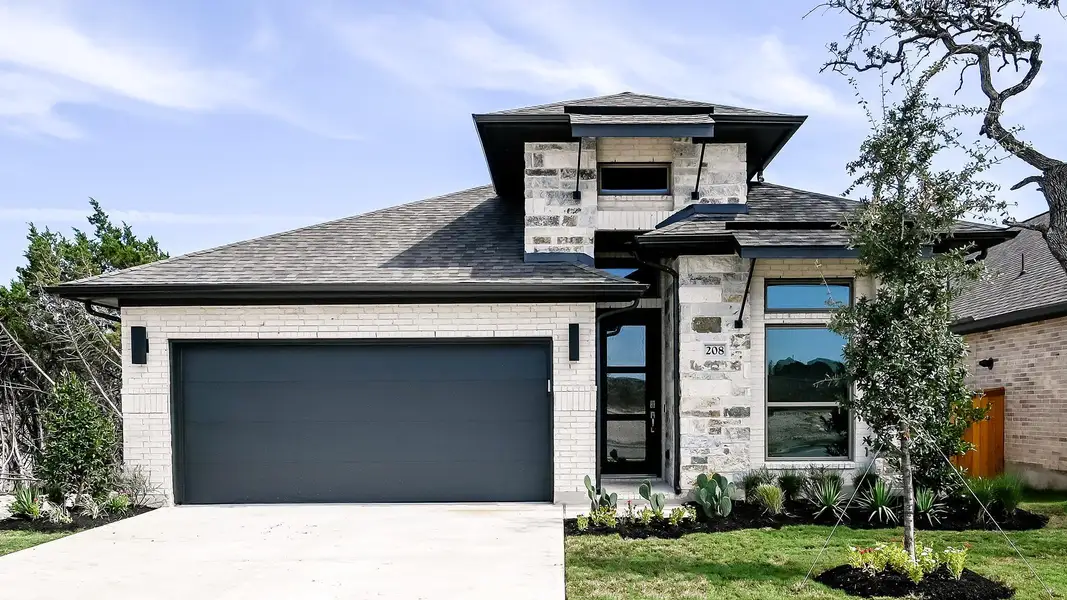 View of front facade with stone siding, concrete driveway, a shingled roof, and an attached garage