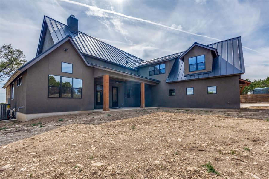 Back of property featuring a patio, a standing seam roof, and a chimney