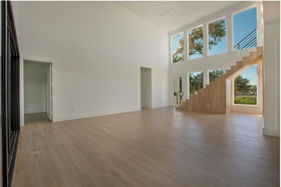 Unfurnished living room with a towering ceiling and light hardwood / wood-style flooring