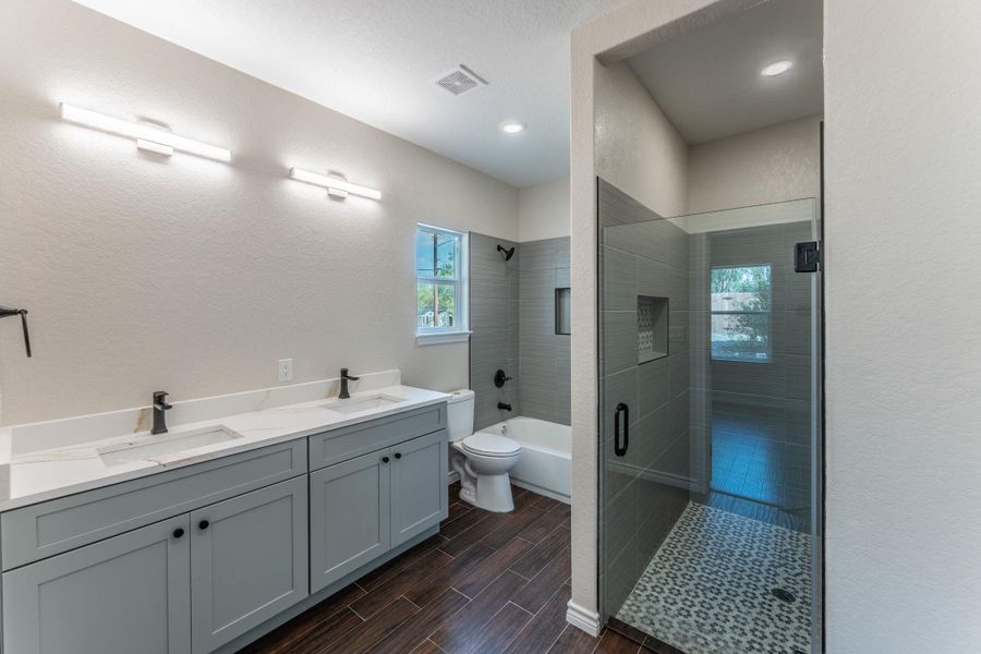 Bathroom featuring a dual vanity with light gray cabinetry, white countertops, and matte black fixtures