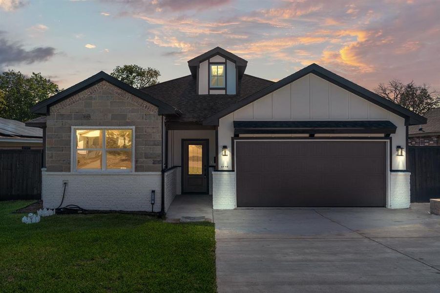 View of front of property with a yard and a garage