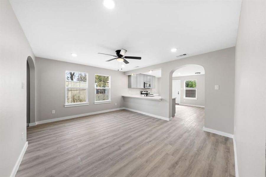 Unfurnished living room featuring arched walkways, light wood-style flooring, recessed lighting, plenty of natural light, and ceiling fan Unfurnished living room featuring arched walkways, light wood-style flooring, recessed lighting, plenty of natural light, and ceiling fan