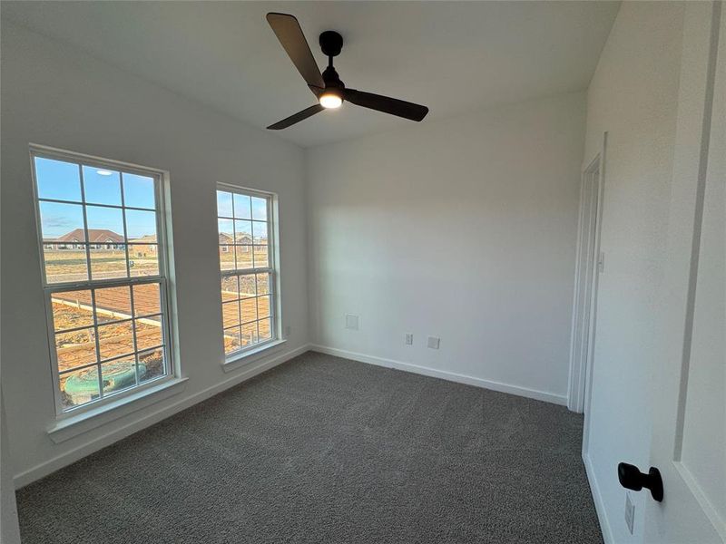 Room 1 with ceiling fan and dark colored carpet