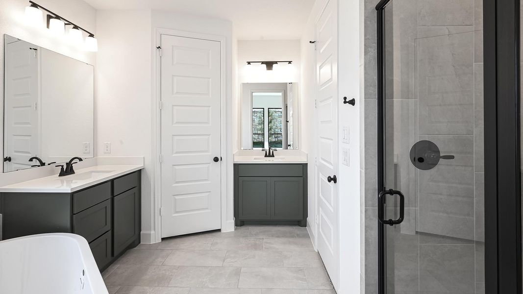 Full bath with a stall shower, two vanities, a freestanding bath, and light tile patterned flooring Full bath with a stall shower, two vanities, a freestanding bath, and light tile patterned flooring