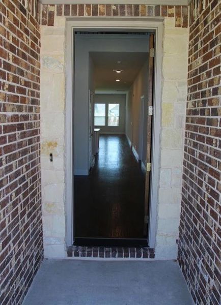 View of doorway to property with hardwood floors