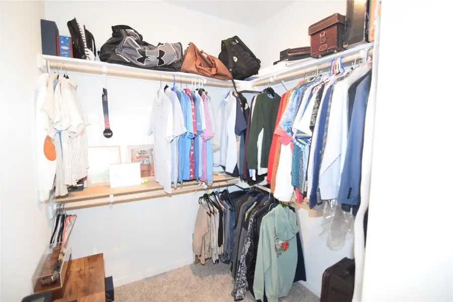 Ample built-in shelving and hanging rods maximize storage space in this carpeted walk-in closet.