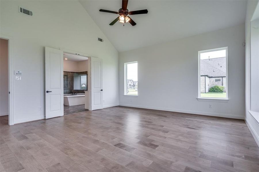 Unfurnished living room with high vaulted ceiling, ceiling fan, and hardwood / wood-style flooring