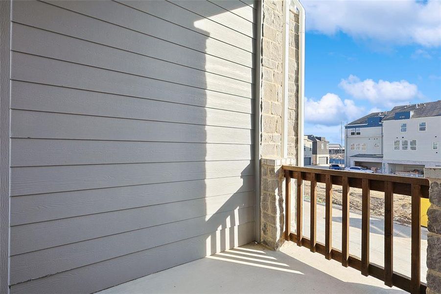 This property features an exterior balcony with a concrete floor, a wooden railing, and stone pillars