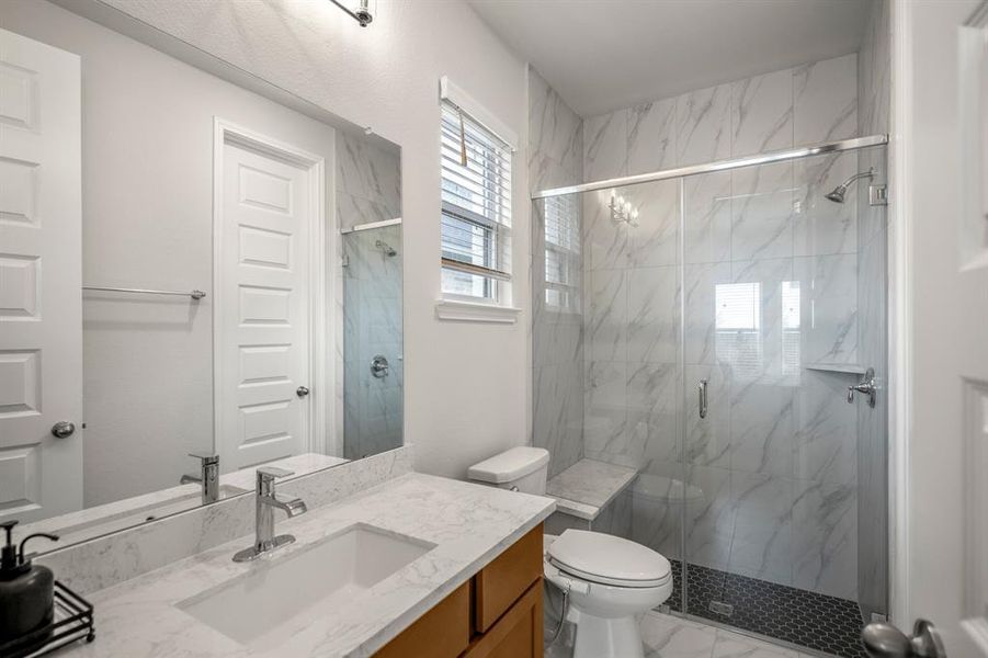 This full bathroom is connected the first secondary bedroom and features a spacious walk-in shower with upgraded tile surround and mudset flooring. It includes a spacious vanity with wood cabinets, quart countertops and large mirror, making it easy to get ready.