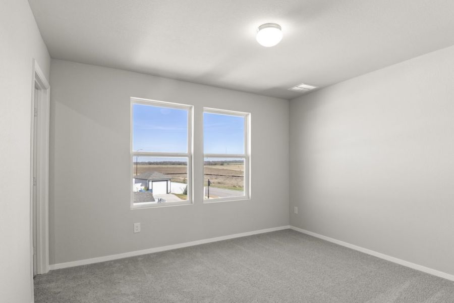 Image of a bedroom with light grey walls, two windows, tan carpeting and white trim