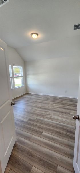 Empty room featuring wood finished floors and lofted ceiling Empty room featuring wood finished floors and lofted ceiling