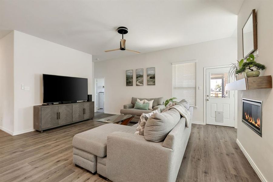 Living room featuring a glass covered fireplace, light wood-style floors, and ceiling fan Living room featuring a glass covered fireplace, light wood-style floors, and ceiling fan