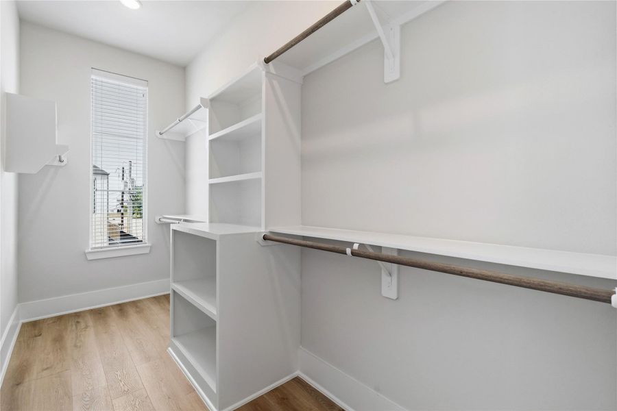 A spacious walk-in closet designed with built-in shelving and multiple hanging areas for everyday organization. A spacious walk-in closet designed with built-in shelving and multiple hanging areas for everyday organization.