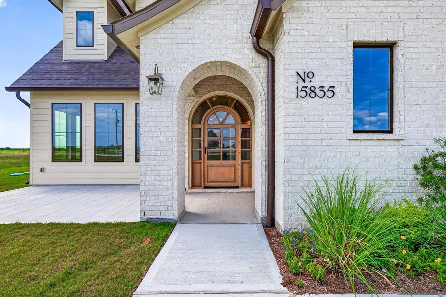 Welcoming front porch entry with an arched walkway leading to the beautiful front door.