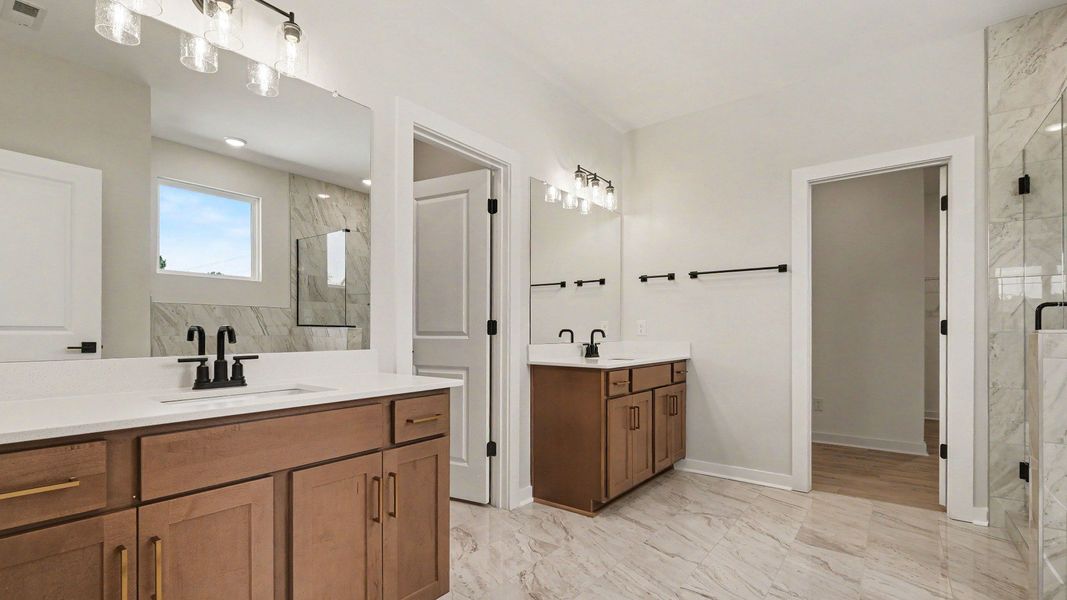 En-suite primary bathroom with tile floor, dual vanities, private toilet room, walk-in closet, tiled shower, and more