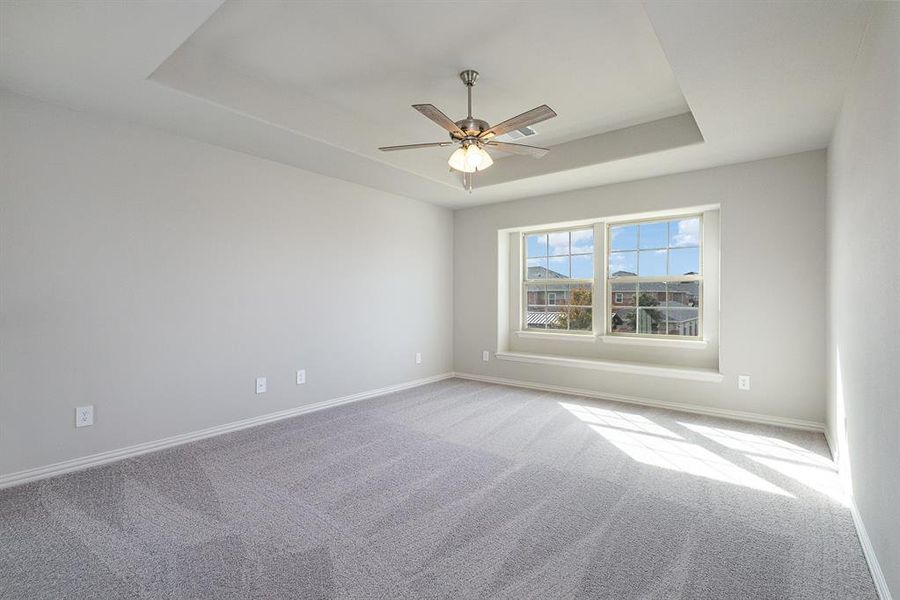 Spare room with ceiling fan, light carpet, and a tray ceiling