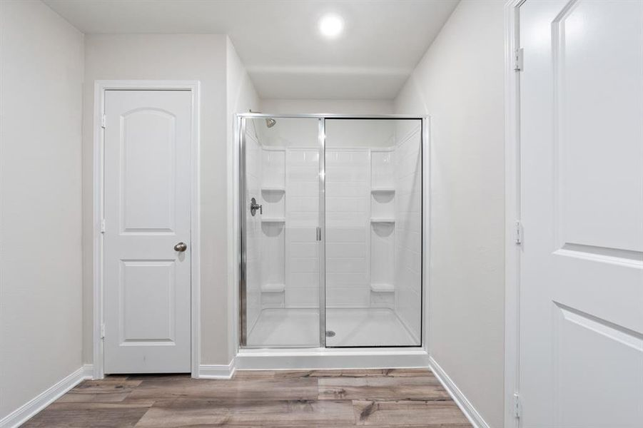 Bathroom featuring hardwood / wood-style floors and a shower with shower door