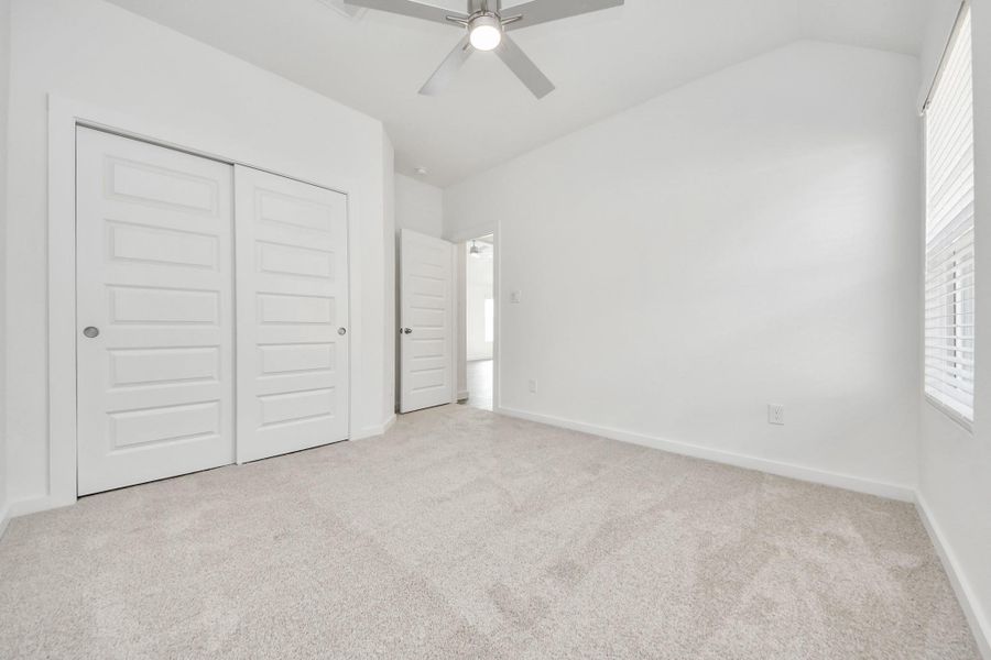 Secondary bedroom features plush carpeting, large windows that let in plenty of natural light, bright paint, and spacious closets.