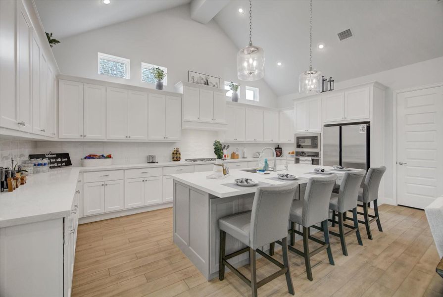 The kitchen features a large island with built-in seating, ample counter space, and a walk-in pantry, creating a highly functional layout that’s perfect for cooking, serving, and gathering.