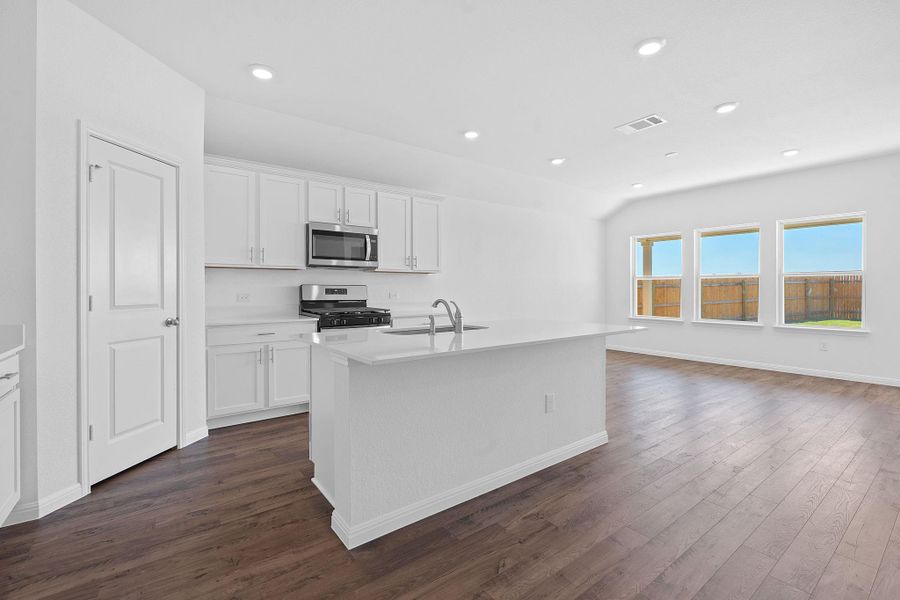 Kitchen with white cabinets, stainless steel appliances, dark wood-type flooring, recessed lighting, and an island with sink