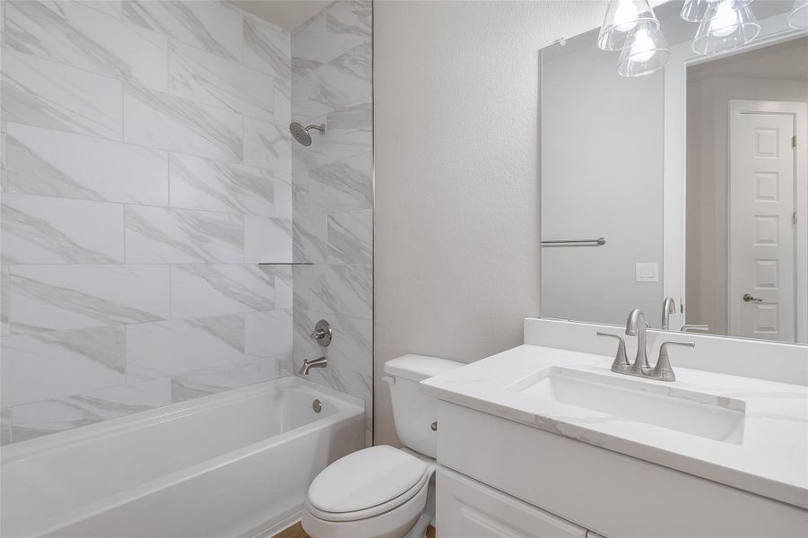 Full secondary bathroom featuring bathtub / shower combo, quartz countertops, modern fixtures, and wood plank tile Full secondary bathroom featuring bathtub / shower combo, quartz countertops, modern fixtures, and wood plank tile
