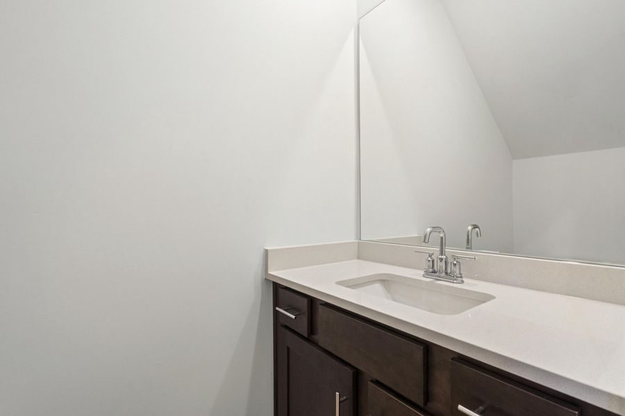 Vanity featuring a chrome faucet, integrated rectangular sink, and light-toned solid surface countertop